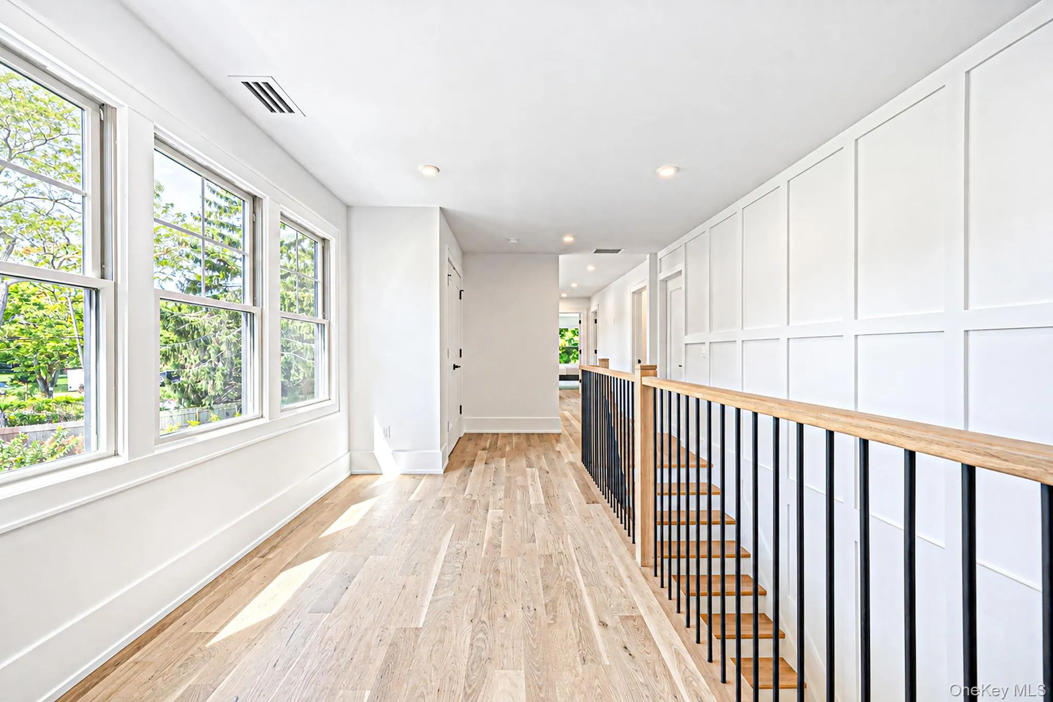 Hardwood flooring, recessed ceiling lighting, multi-pane windows, wainscoting, and a wood and metal stair railing Hardwood flooring, recessed ceiling lighting, multi-pane windows, wainscoting, and a wood and metal stair railing