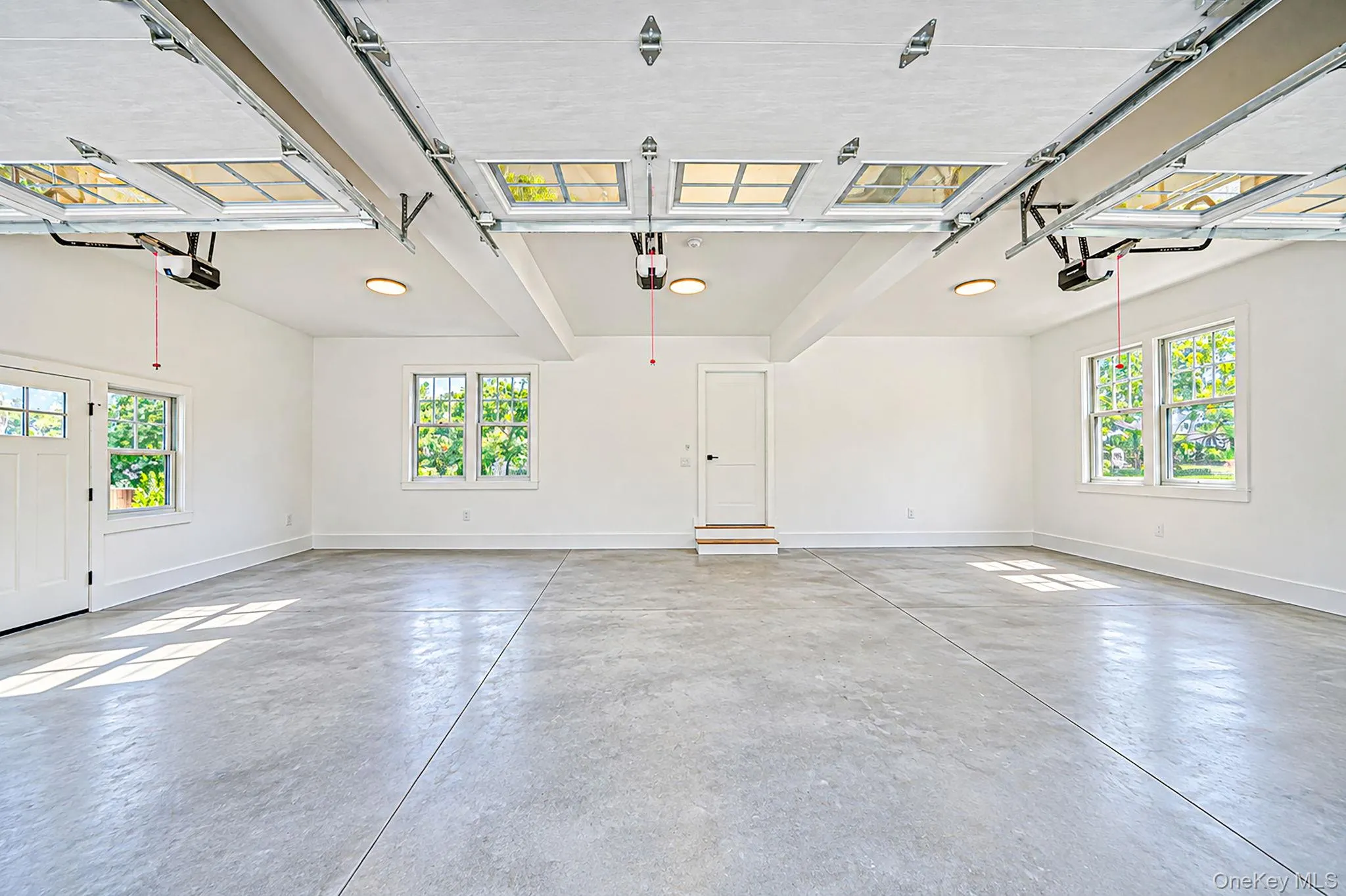 3 car garage, Expansive concrete flooring with multiple windows, overhead lighting, and two garage door openers 3 car garage, Expansive concrete flooring with multiple windows, overhead lighting, and two garage door openers