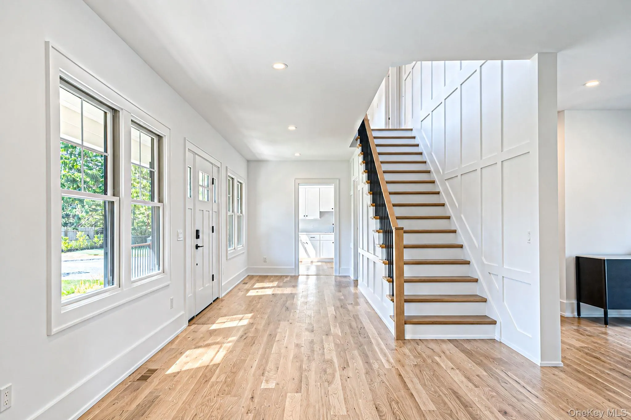 Hardwood flooring throughout, white paneled wall detailing, recessed lighting, white trim windows, and a craftsman-style front door Hardwood flooring throughout, white paneled wall detailing, recessed lighting, white trim windows, and a craftsman-style front door