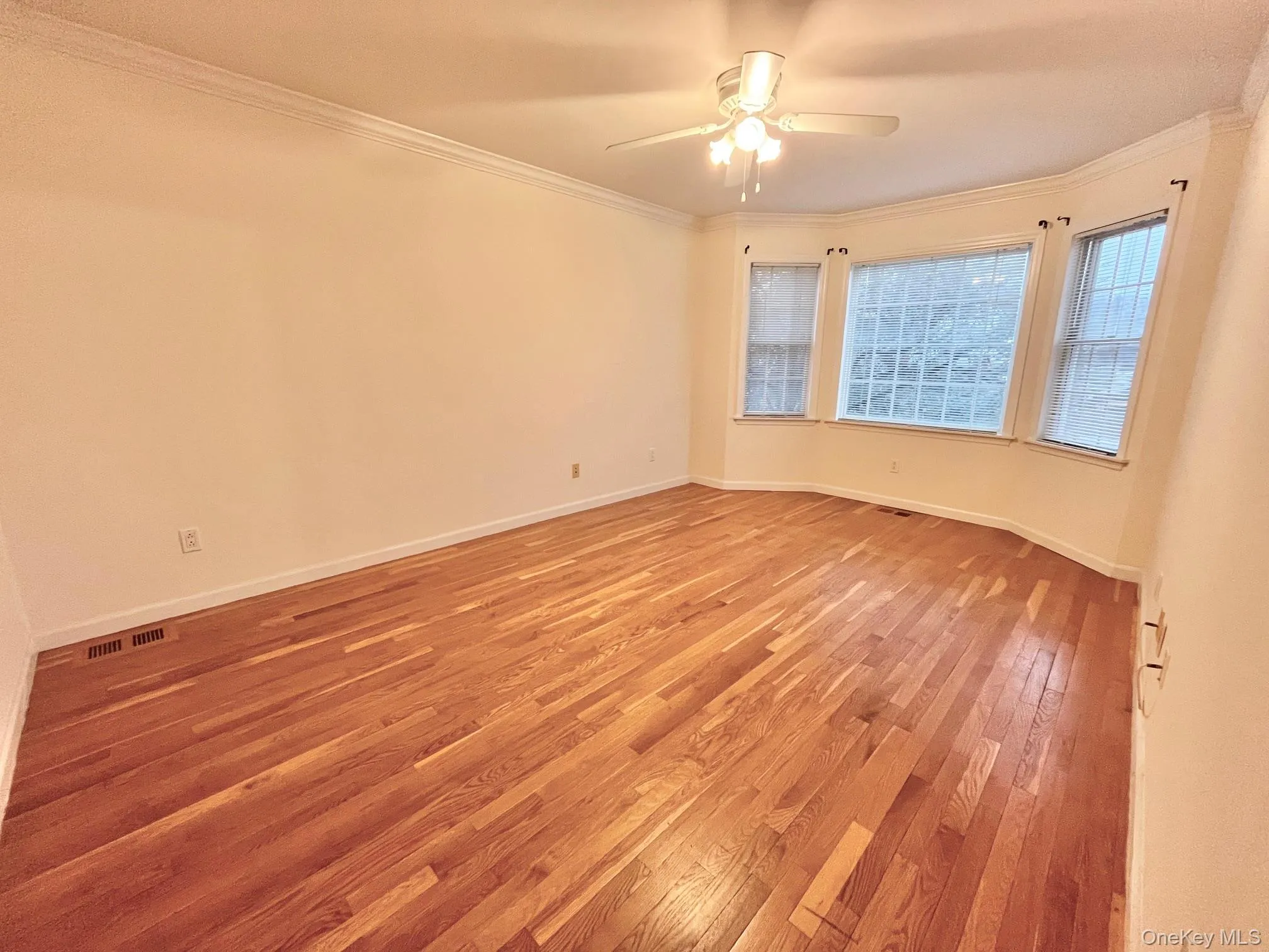 Spare room featuring ornamental molding, light wood-style floors, and a ceiling fan Spare room featuring ornamental molding, light wood-style floors, and a ceiling fan