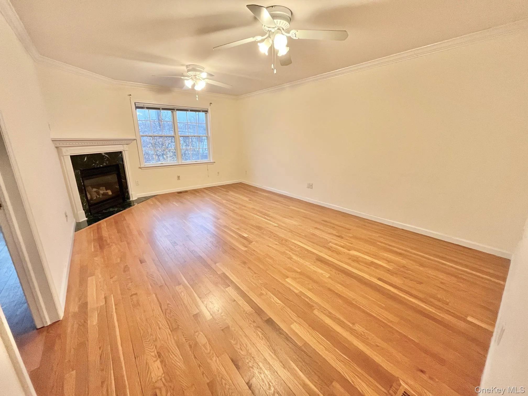 Unfurnished living room featuring crown molding, a high end fireplace, light wood finished floors, and a ceiling fan Unfurnished living room featuring crown molding, a high end fireplace, light wood finished floors, and a ceiling fan
