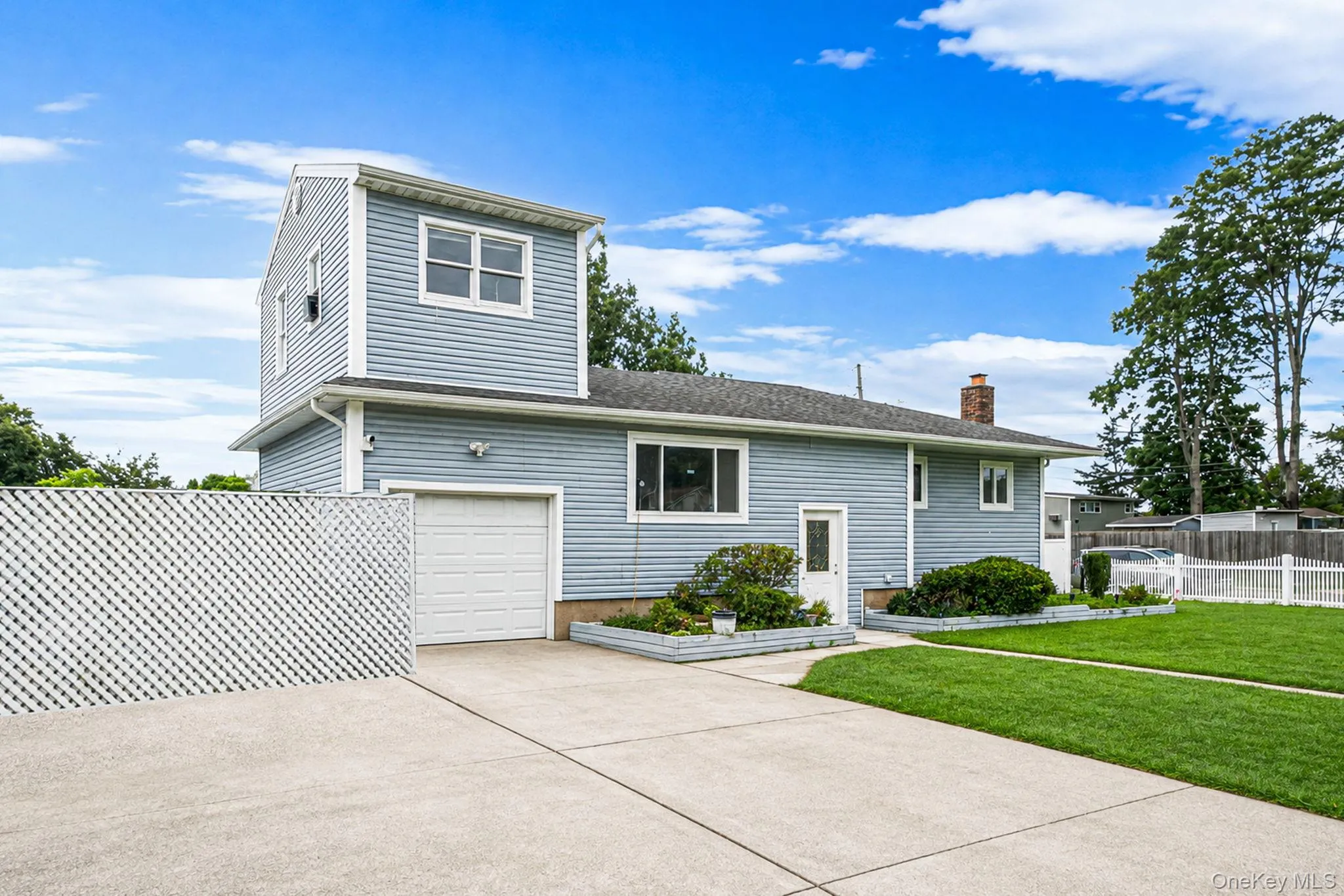Two-story siding exterior with an attached garage, paved driveway, and established landscaping Two-story siding exterior with an attached garage, paved driveway, and established landscaping
