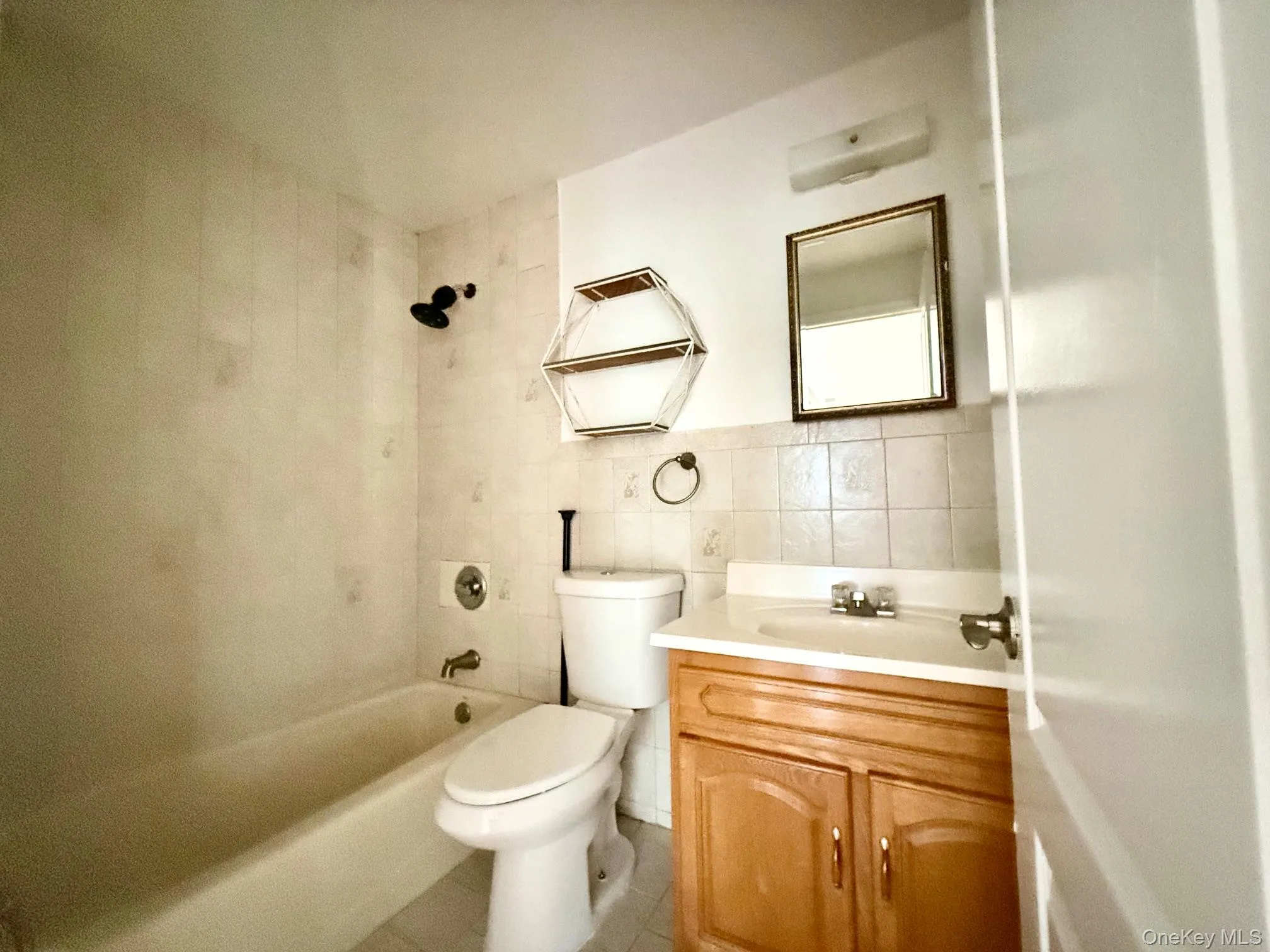 Bathroom featuring a built-in bathtub with shower, toilet, and vanity with a sink and storage Bathroom featuring a built-in bathtub with shower, toilet, and vanity with a sink and storage