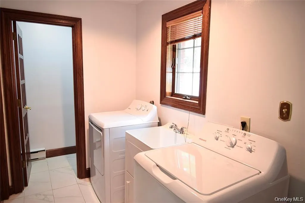 Laundry room featuring a baseboard radiator, washer and dryer, and light marble finish flooring Laundry room featuring a baseboard radiator, washer and dryer, and light marble finish flooring