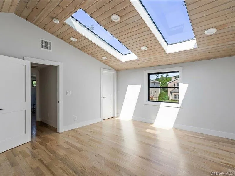 Vaulted wood-finish ceiling, hardwood flooring, two skylights, recessed lighting, and a black-framed window Vaulted wood-finish ceiling, hardwood flooring, two skylights, recessed lighting, and a black-framed window