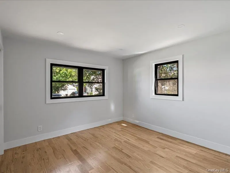 Hardwood flooring with a natural finish, recessed ceiling lighting, and multiple windows with black frames Hardwood flooring with a natural finish, recessed ceiling lighting, and multiple windows with black frames