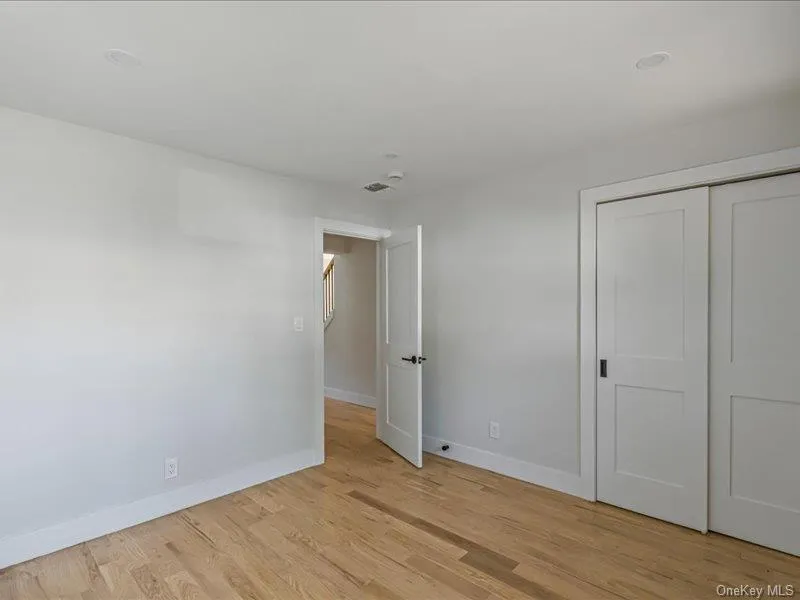 Wood-finish flooring, recessed lighting, white walls, and white sliding closet doors Wood-finish flooring, recessed lighting, white walls, and white sliding closet doors