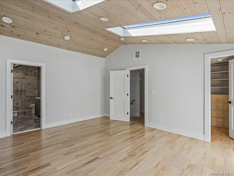 Vaulted wood-paneled ceiling with recessed lighting and skylights, wood-finish flooring, and built-in closet shelving Vaulted wood-paneled ceiling with recessed lighting and skylights, wood-finish flooring, and built-in closet shelving