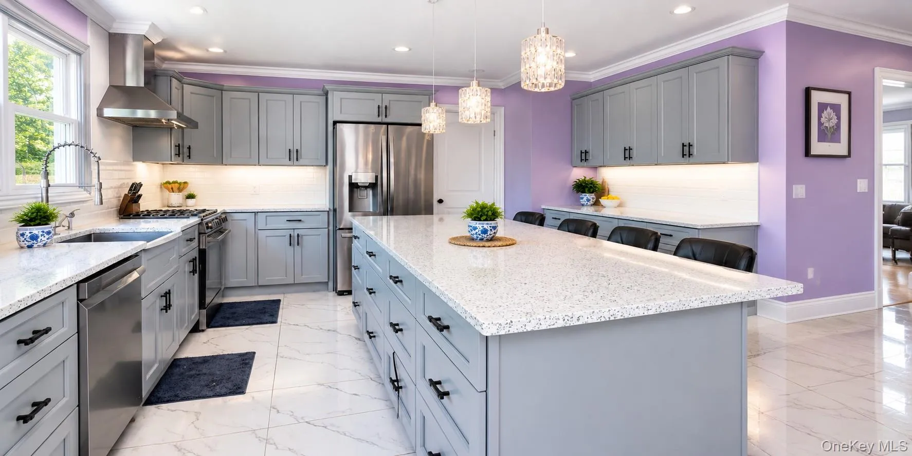 Kitchen featuring stainless steel appliances, an expansive island with seating, pendant lighting fixtures, light-toned countertops. Kitchen featuring stainless steel appliances, an expansive island with seating, pendant lighting fixtures, light-toned countertops.