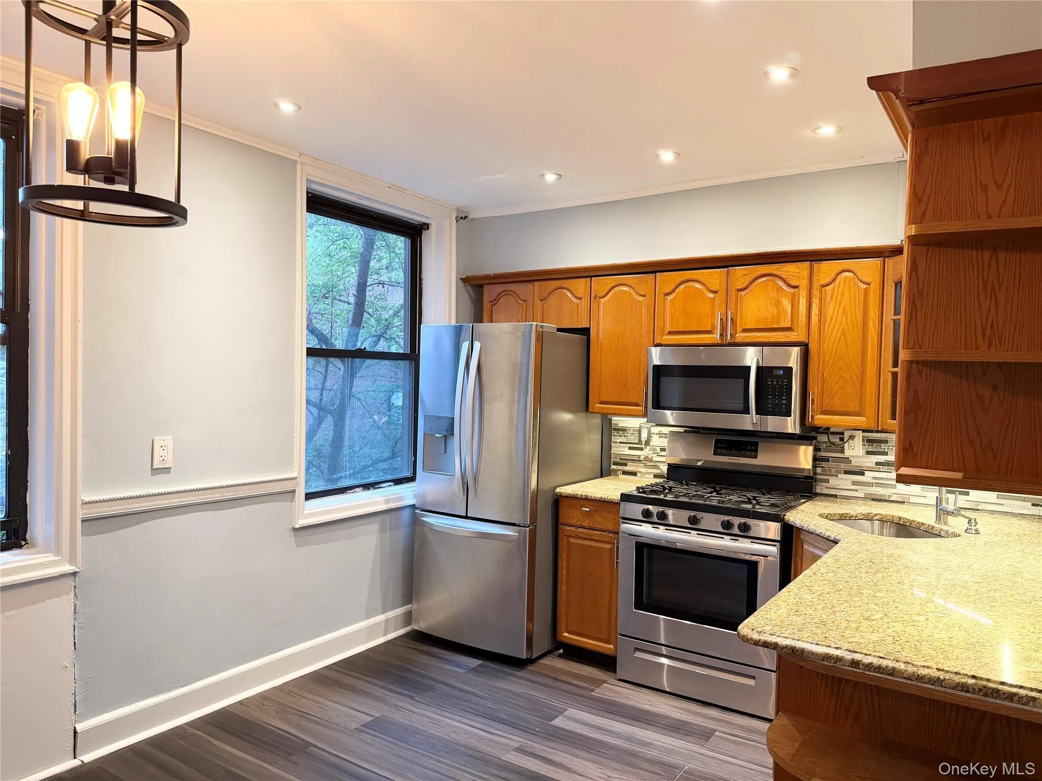 Kitchen featuring wood-finish cabinetry, stainless steel appliances, and a tiled backsplash Kitchen featuring wood-finish cabinetry, stainless steel appliances, and a tiled backsplash