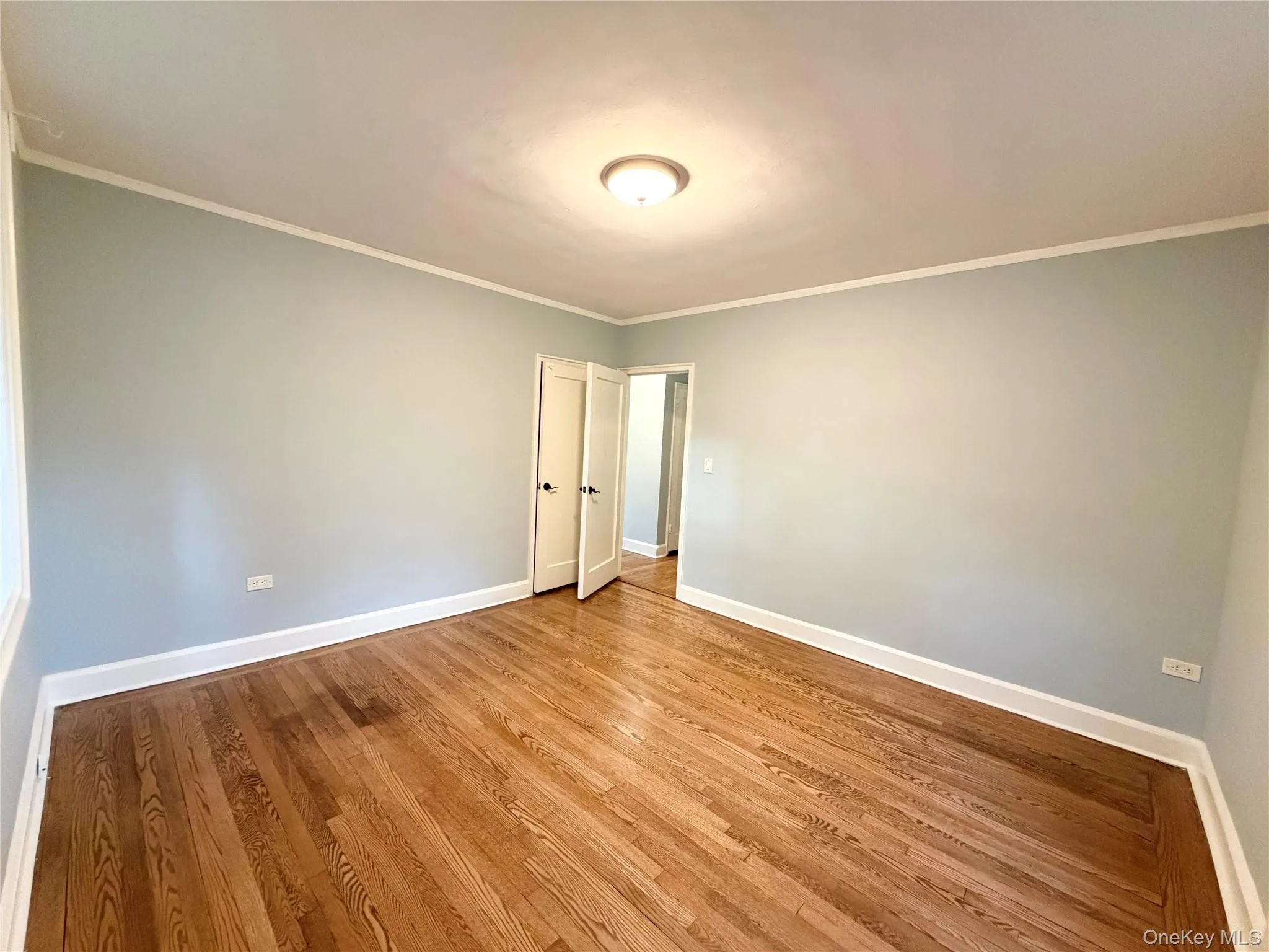 Hardwood flooring, light blue wall paint, white trim, semi-flush mount ceiling light, and double interior doors. Hardwood flooring, light blue wall paint, white trim, semi-flush mount ceiling light, and double interior doors.