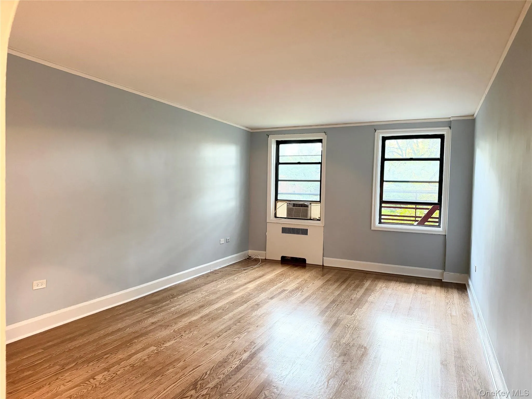 Hardwood flooring, painted walls, crown molding, and two windows Hardwood flooring, painted walls, crown molding, and two windows