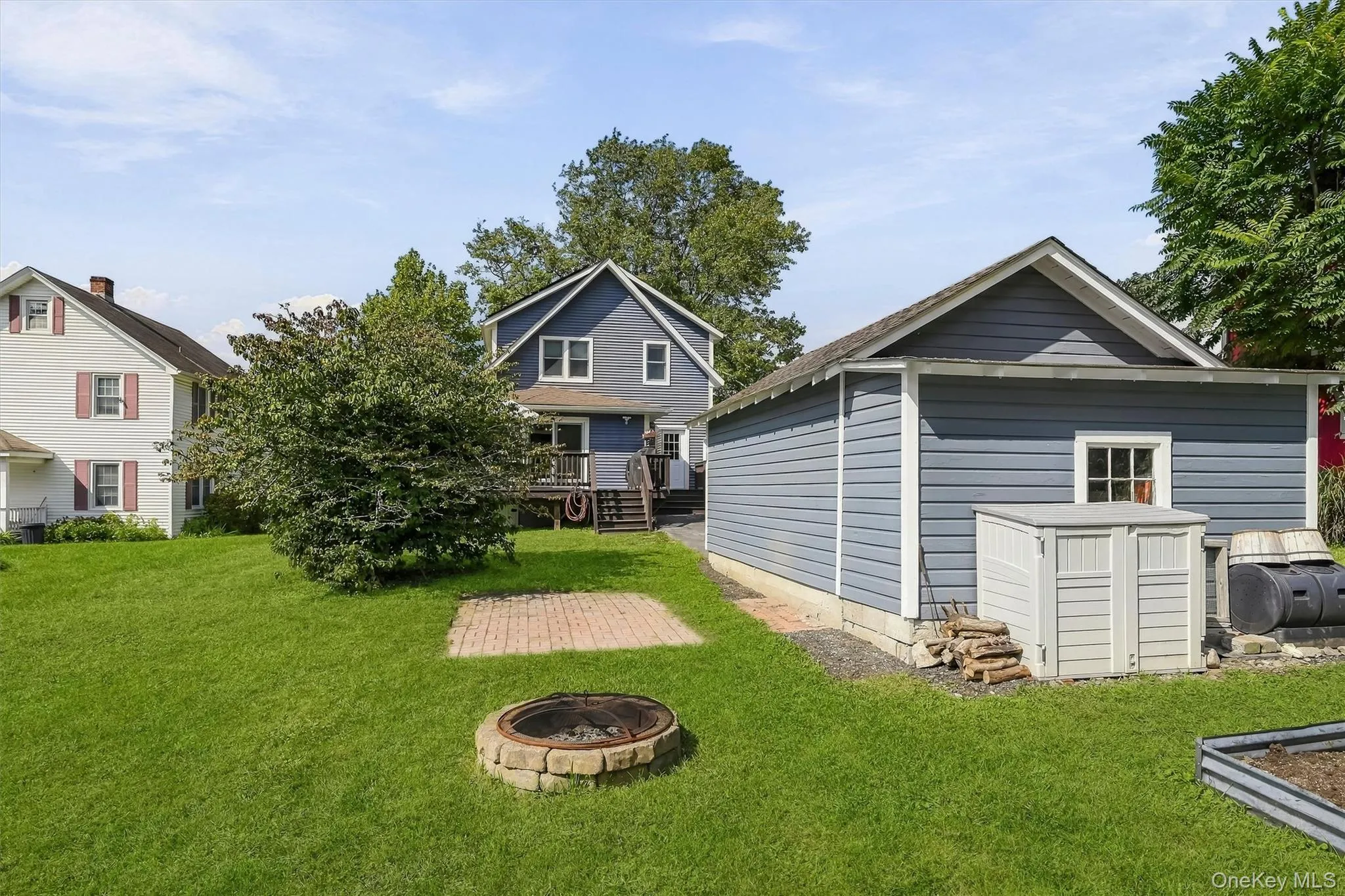 Expansive lawn featuring a paver patio and a stone fire pit Expansive lawn featuring a paver patio and a stone fire pit