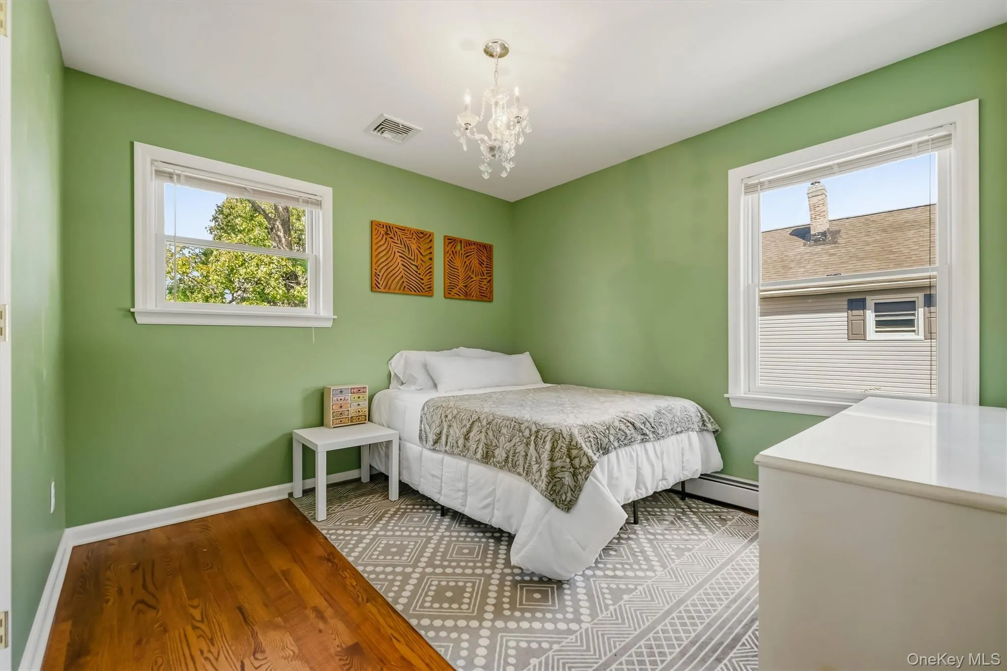 Wood-finish flooring, two windows with white trim, and a decorative ceiling light fixture Wood-finish flooring, two windows with white trim, and a decorative ceiling light fixture