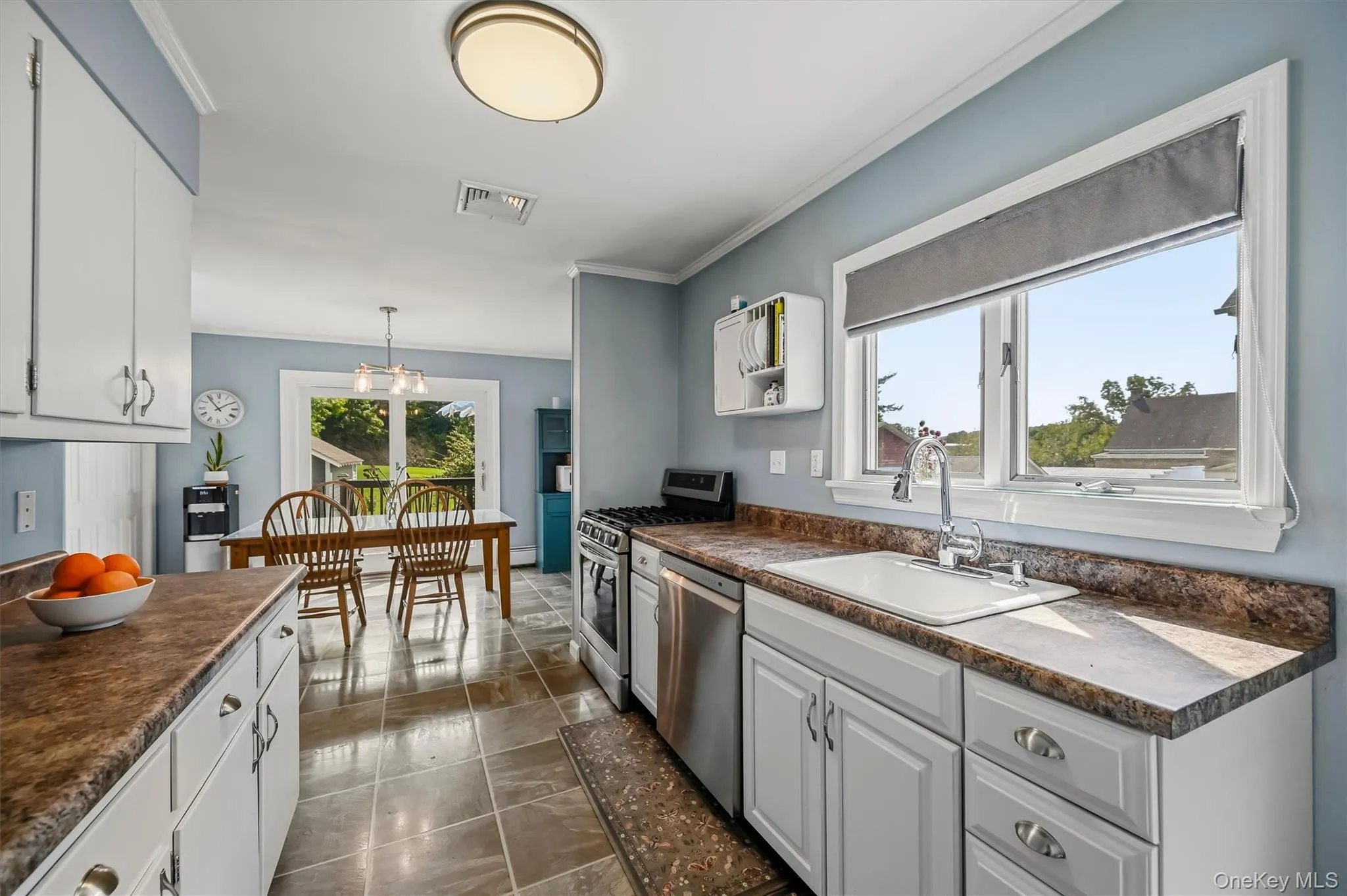 White cabinetry with brushed nickel hardware, laminate countertops, stainless steel appliances, and tiled flooring White cabinetry with brushed nickel hardware, laminate countertops, stainless steel appliances, and tiled flooring
