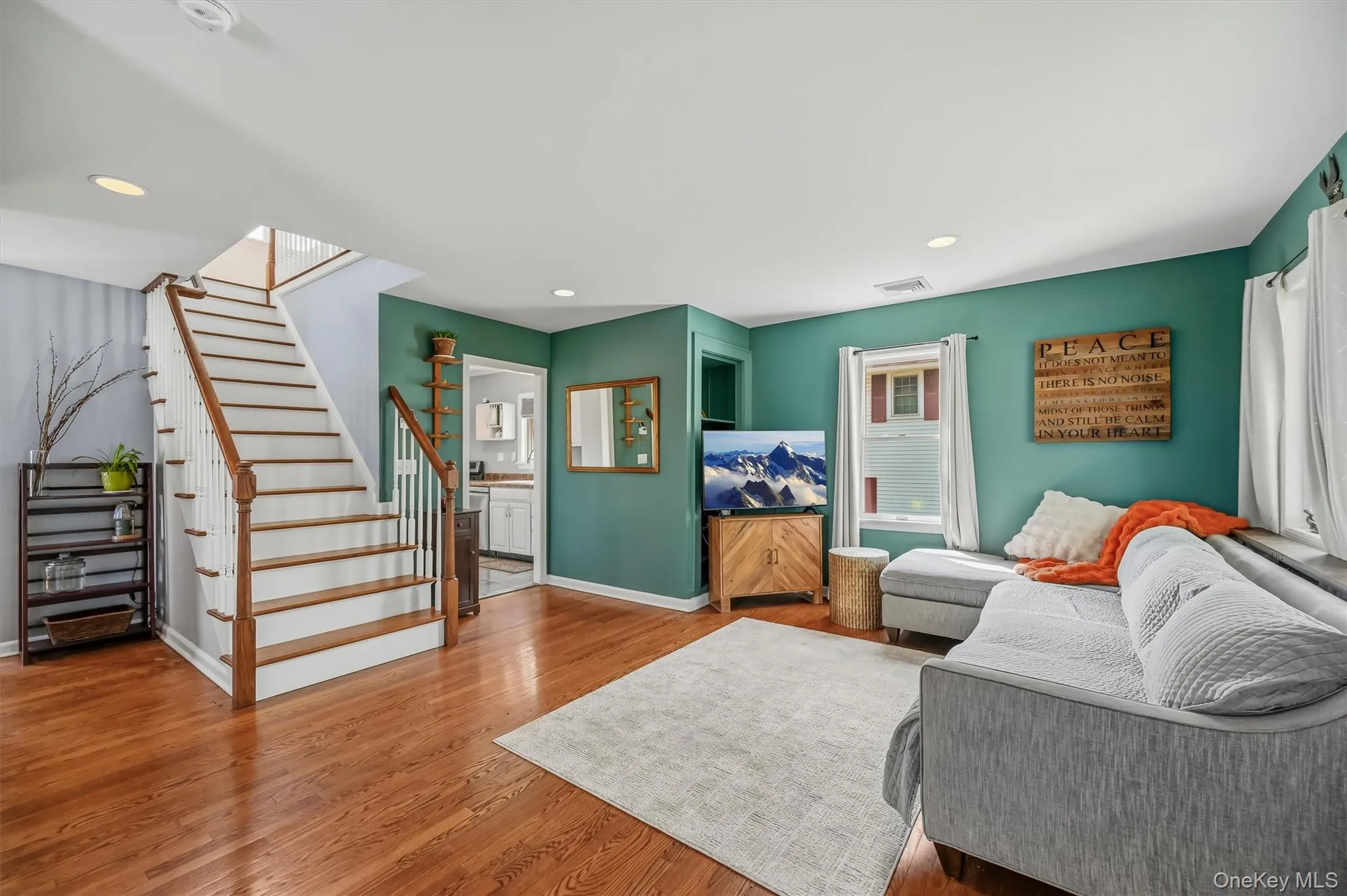 Hardwood flooring, painted interior walls, staircase with wood handrails, recessed ceiling lighting, and multiple windows Hardwood flooring, painted interior walls, staircase with wood handrails, recessed ceiling lighting, and multiple windows