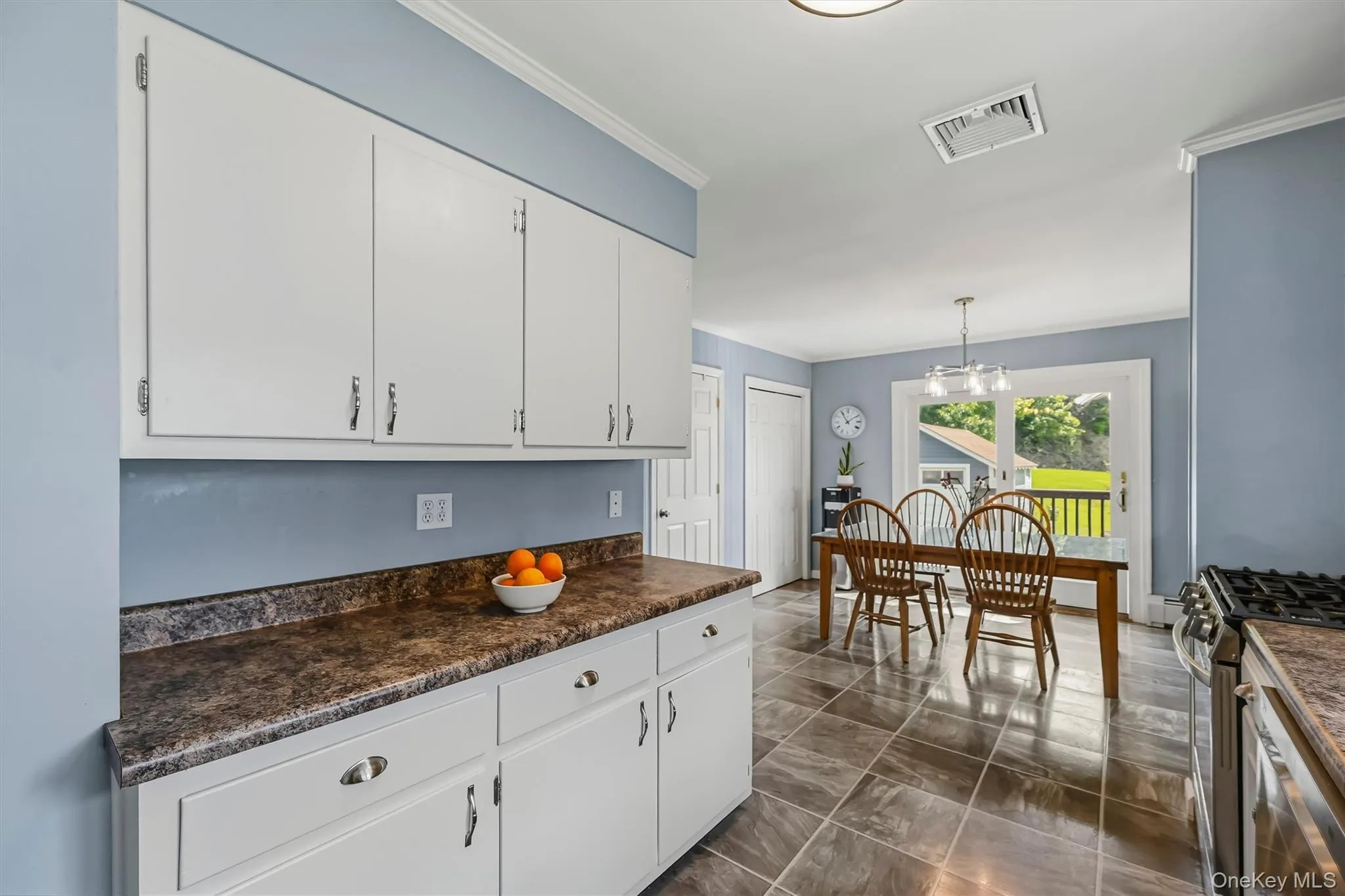 White cabinetry with matte silver hardware, dark patterned countertops, tile flooring, and a glass-paned door White cabinetry with matte silver hardware, dark patterned countertops, tile flooring, and a glass-paned door