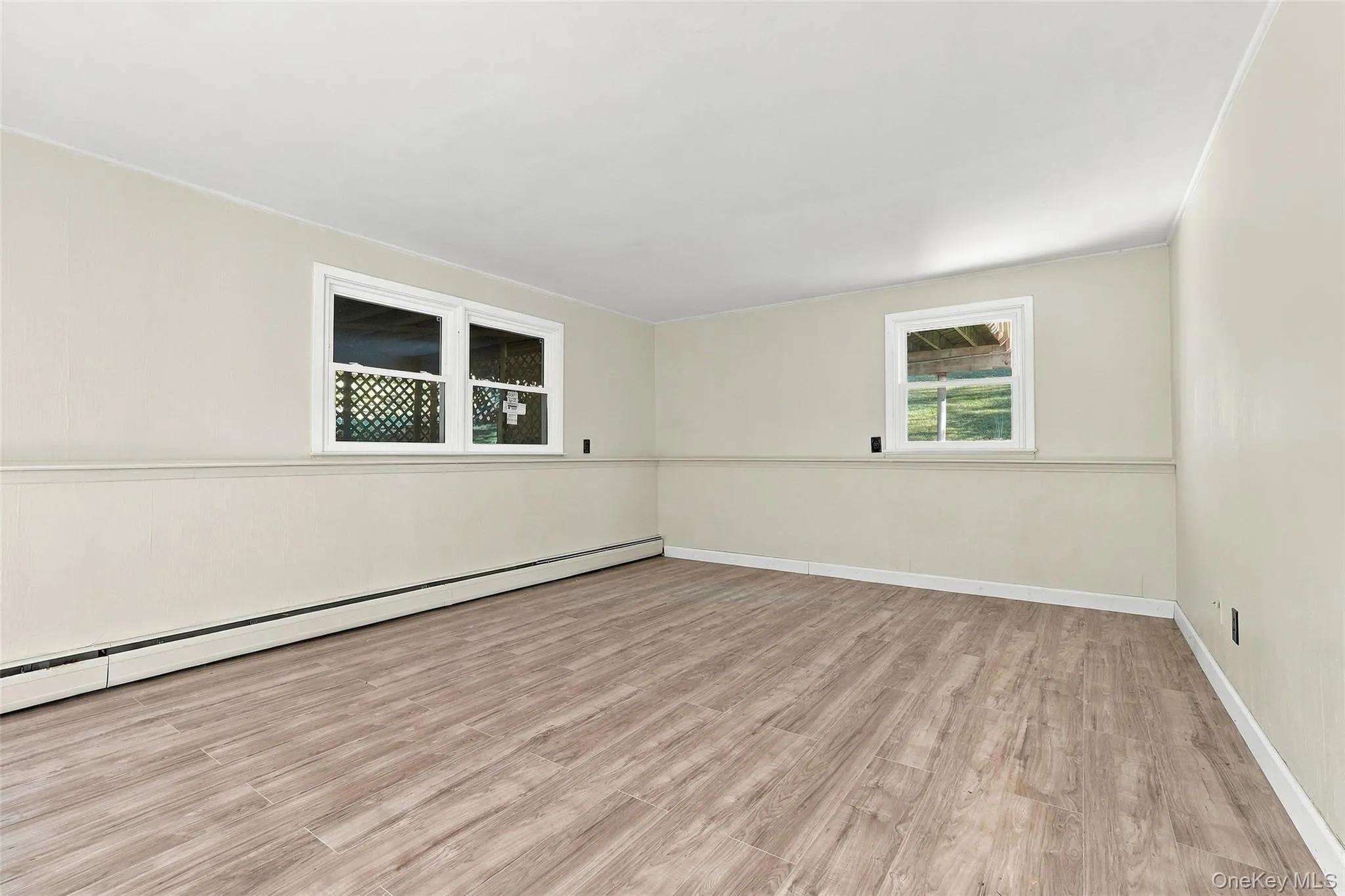 Lower Level with Woodlike-finish flooring, neutral wall tones, white trim, and multiple windows Lower Level with Woodlike-finish flooring, neutral wall tones, white trim, and multiple windows