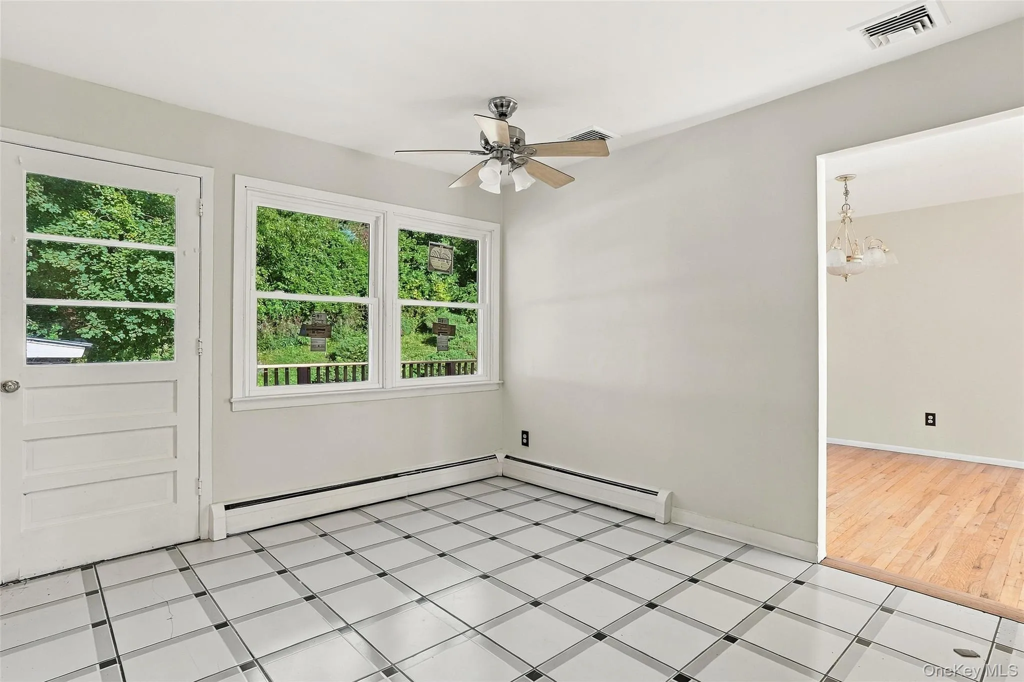 Kitchen with patterned tile flooring, ceiling fan, multiple windows, panel door with glass insert, wood-finish flooring in adjacent area Kitchen with patterned tile flooring, ceiling fan, multiple windows, panel door with glass insert, wood-finish flooring in adjacent area