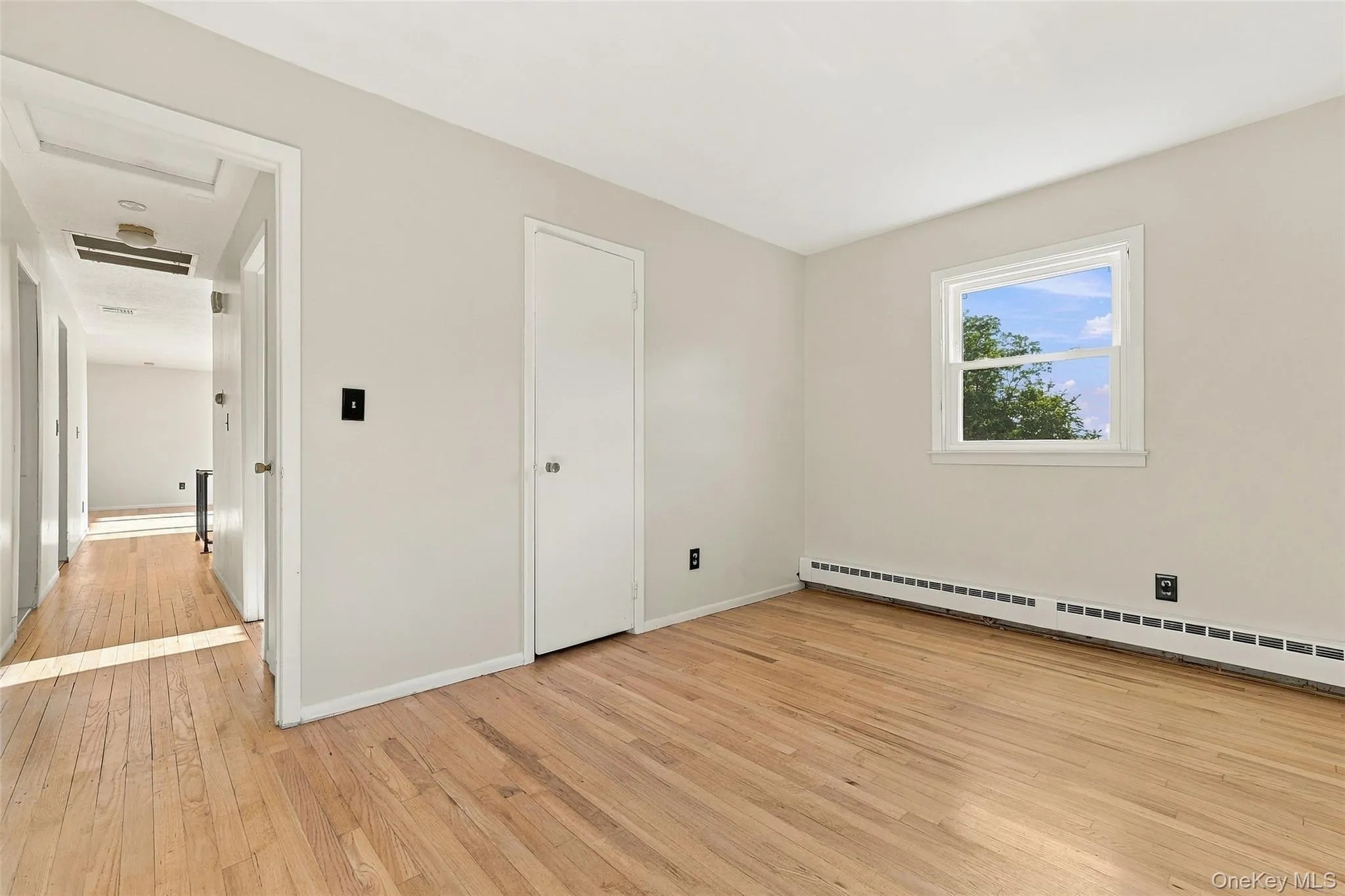 Bedroom with Light wood-finish flooring, white walls, and a single window with white trim Bedroom with Light wood-finish flooring, white walls, and a single window with white trim