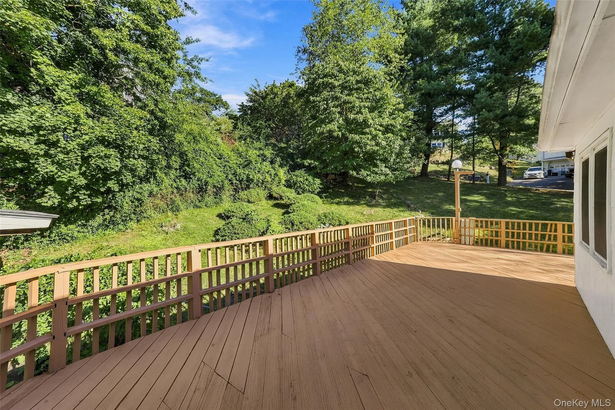 Expansive wood deck with wood railings, surrounded by mature trees and greenery Expansive wood deck with wood railings, surrounded by mature trees and greenery