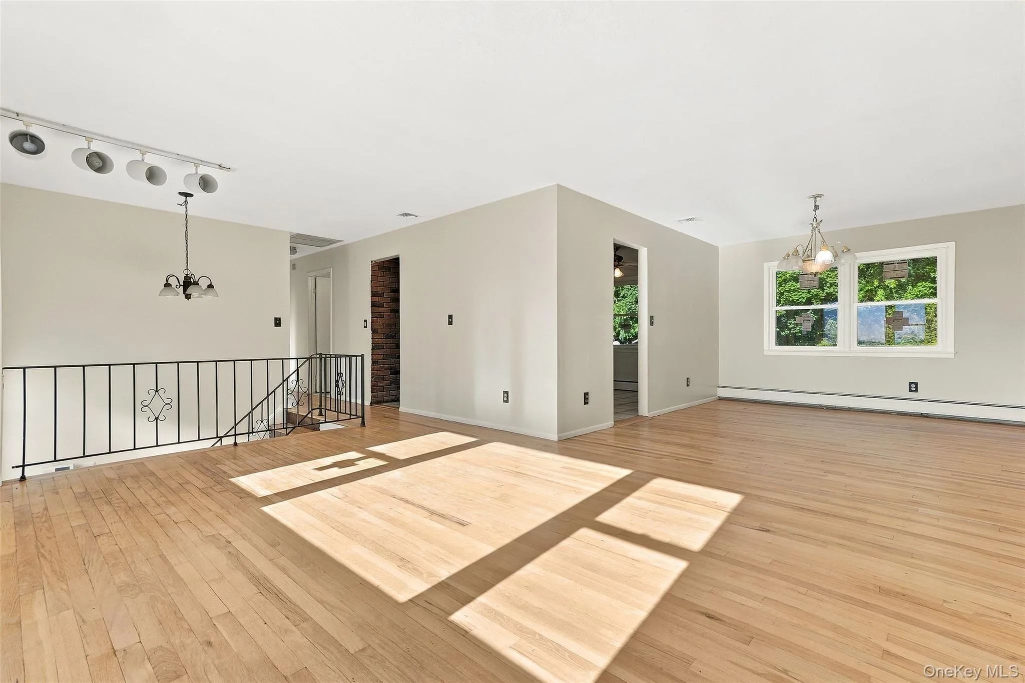 Dining Area with Hardwood flooring, light-toned walls, multiple windows, a chandelier, and a black wrought iron railing Dining Area with Hardwood flooring, light-toned walls, multiple windows, a chandelier, and a black wrought iron railing