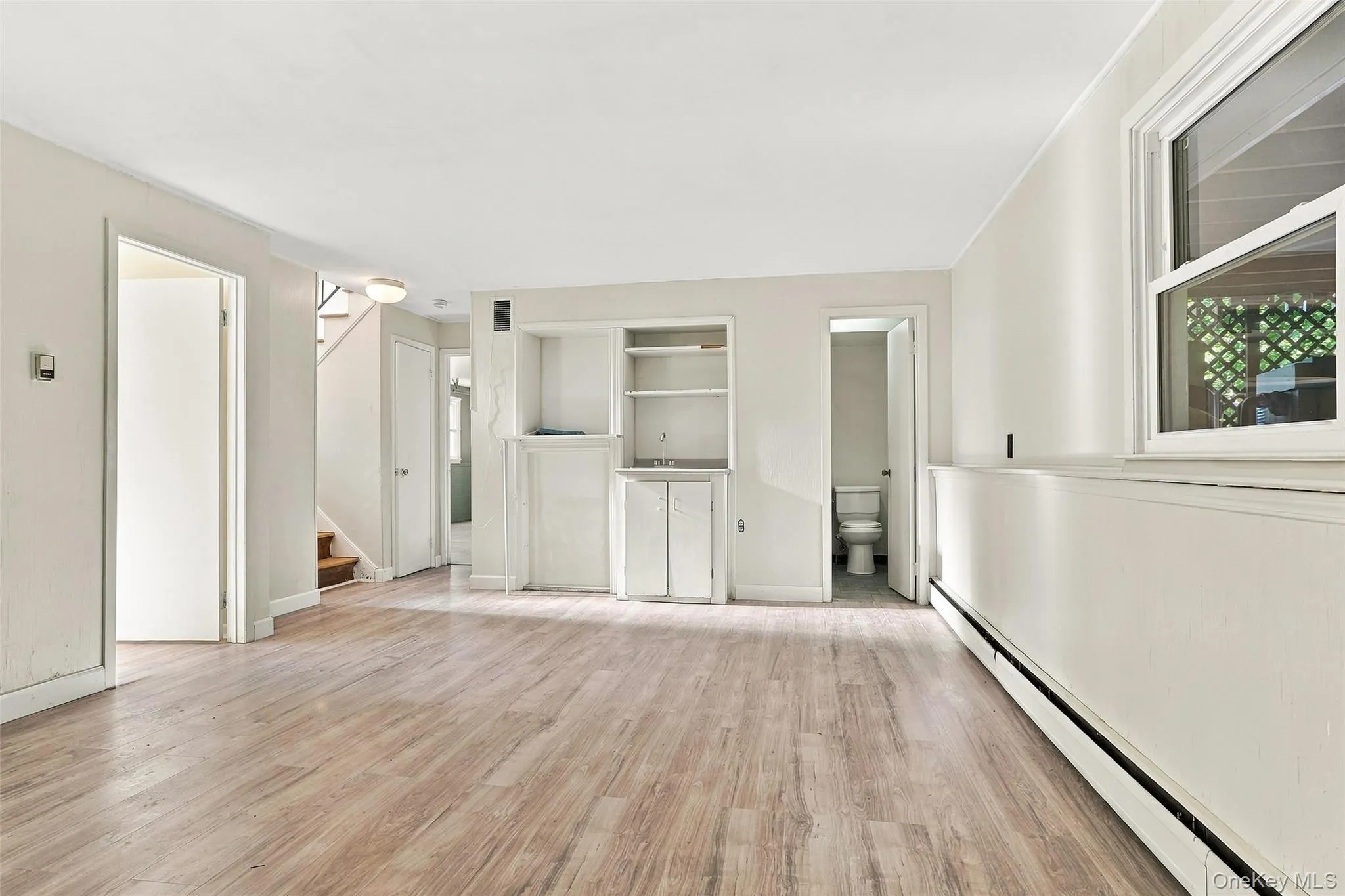 Lower level with Woodlike-finish flooring throughout, integrated built-in shelving, white trim, and a window with natural light Lower level with Woodlike-finish flooring throughout, integrated built-in shelving, white trim, and a window with natural light
