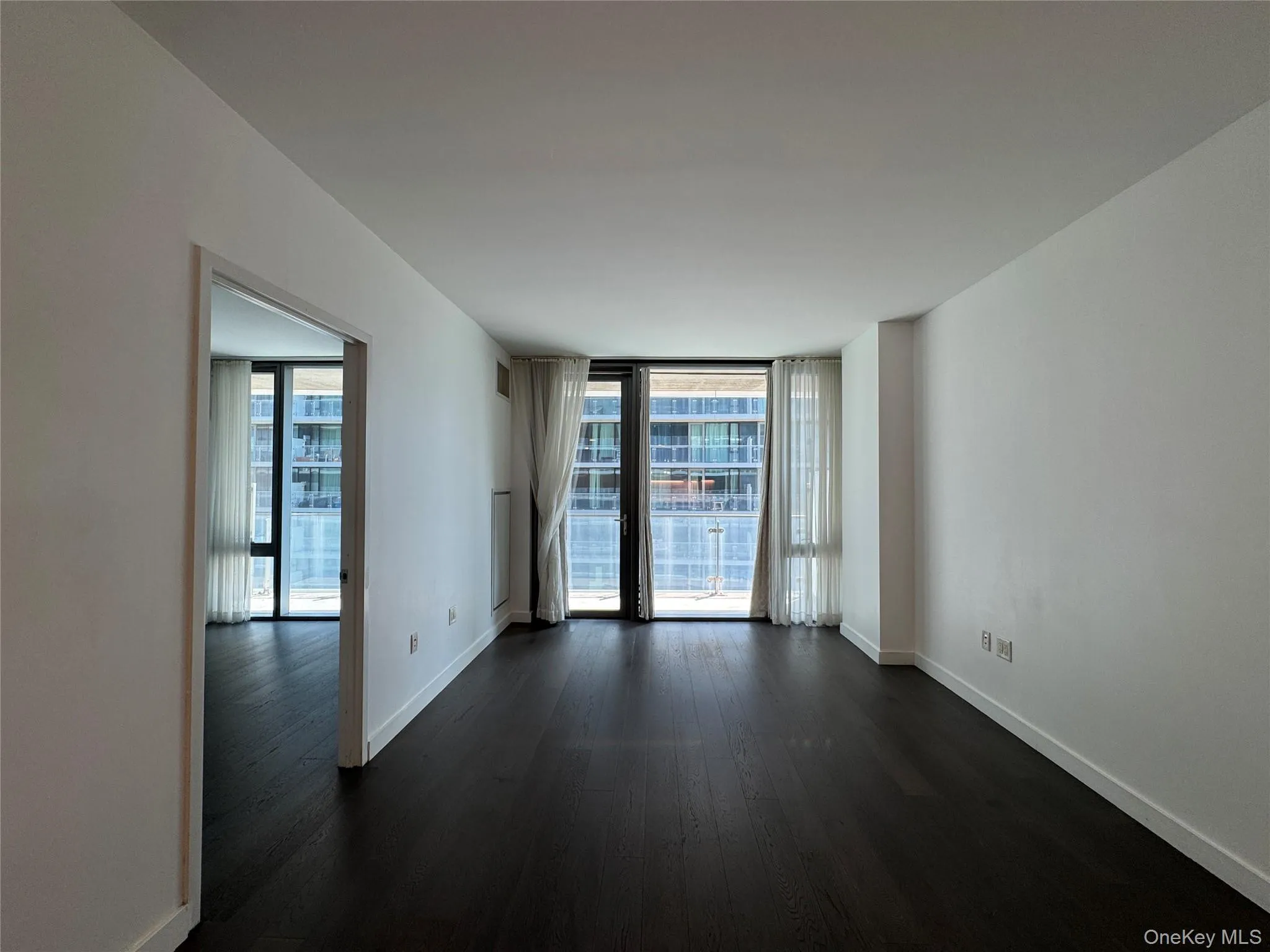 Hardwood flooring, floor-to-ceiling windows, and white walls Hardwood flooring, floor-to-ceiling windows, and white walls