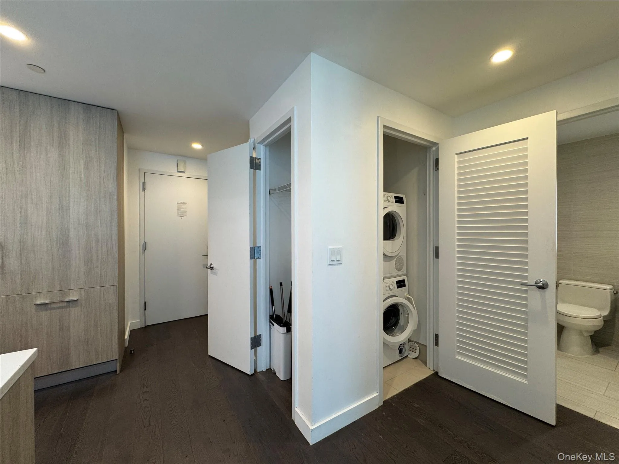 Wood-finish flooring throughout, integrated wood-grain cabinetry, recessed ceiling lighting, and a stacked in-unit washer and dryer Wood-finish flooring throughout, integrated wood-grain cabinetry, recessed ceiling lighting, and a stacked in-unit washer and dryer