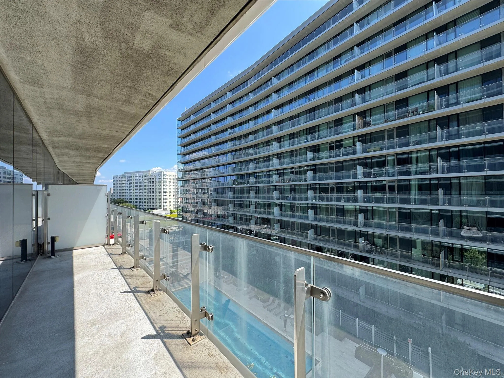 Expansive balcony with a concrete floor, glass and metal railing, and an overhead concrete soffit Expansive balcony with a concrete floor, glass and metal railing, and an overhead concrete soffit