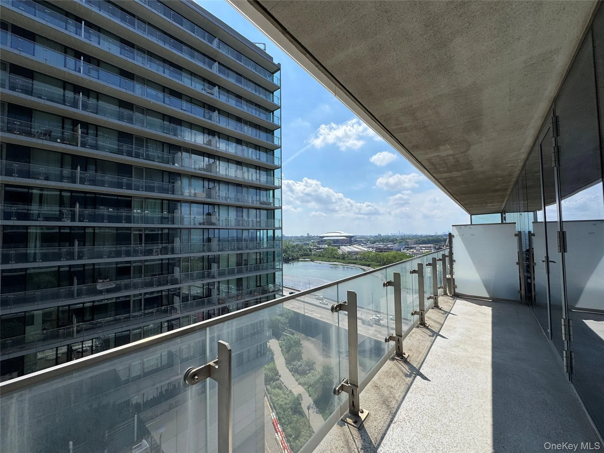 Expansive outdoor balcony with glass railings and a textured concrete floor Expansive outdoor balcony with glass railings and a textured concrete floor