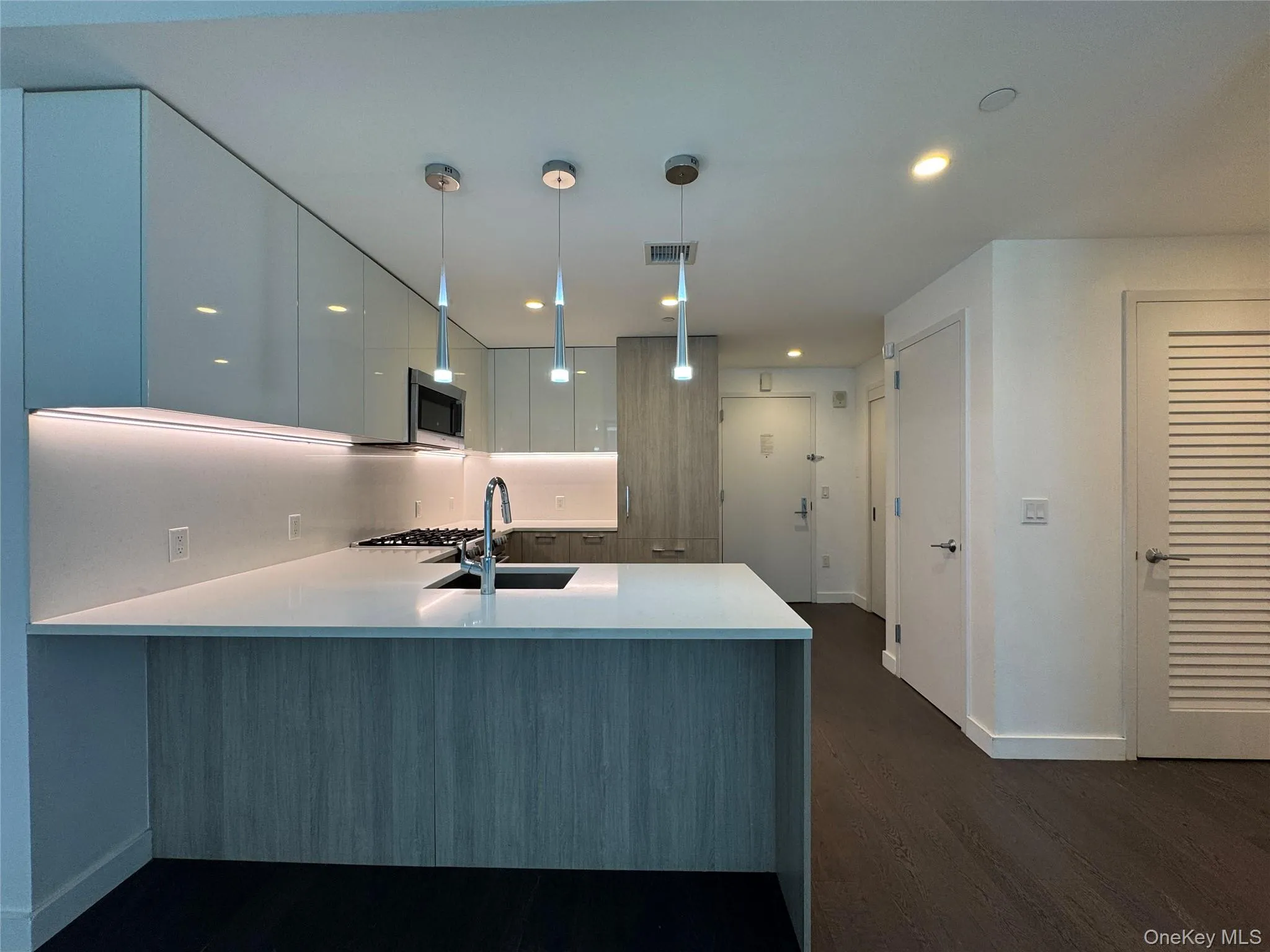 Contemporary kitchen with glossy white cabinetry, undermount sink, stainless steel appliances, and a central island with a light wood-finish base Contemporary kitchen with glossy white cabinetry, undermount sink, stainless steel appliances, and a central island with a light wood-finish base