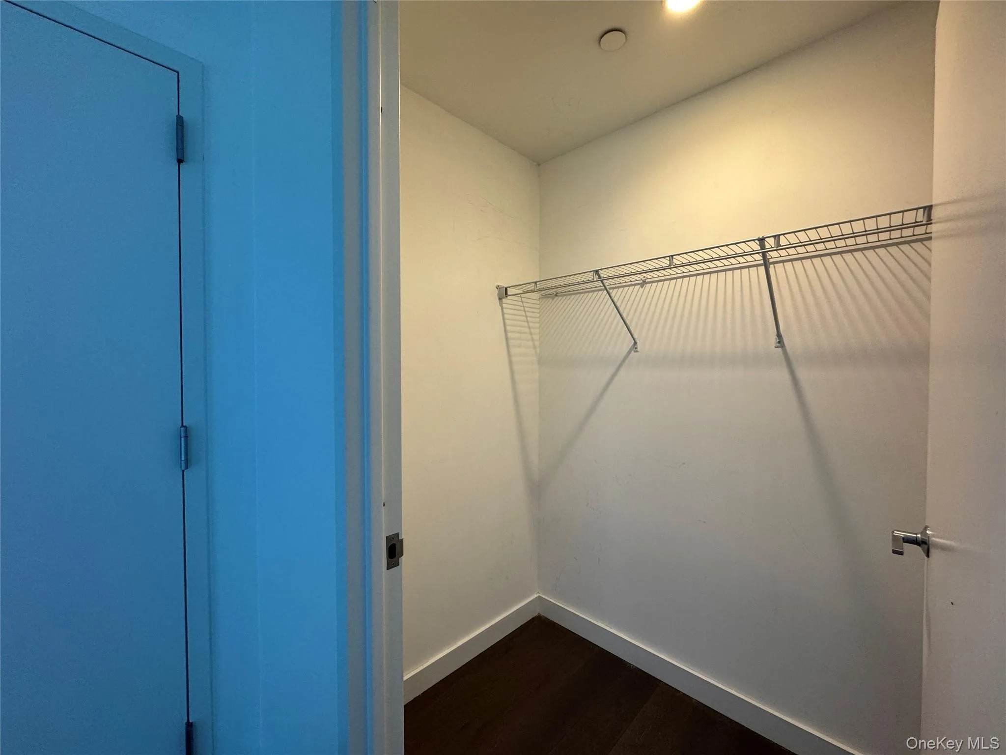 Wire shelving, dark wood-finish flooring, white walls, flush-mount ceiling light Wire shelving, dark wood-finish flooring, white walls, flush-mount ceiling light