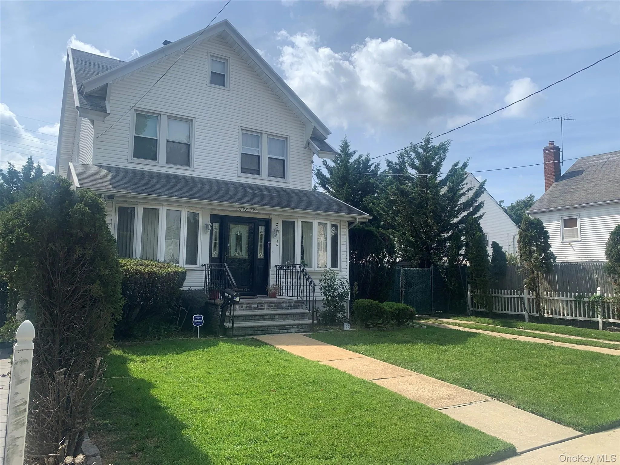 White siding exterior with a front bay window, gabled roofline, and established front yard White siding exterior with a front bay window, gabled roofline, and established front yard
