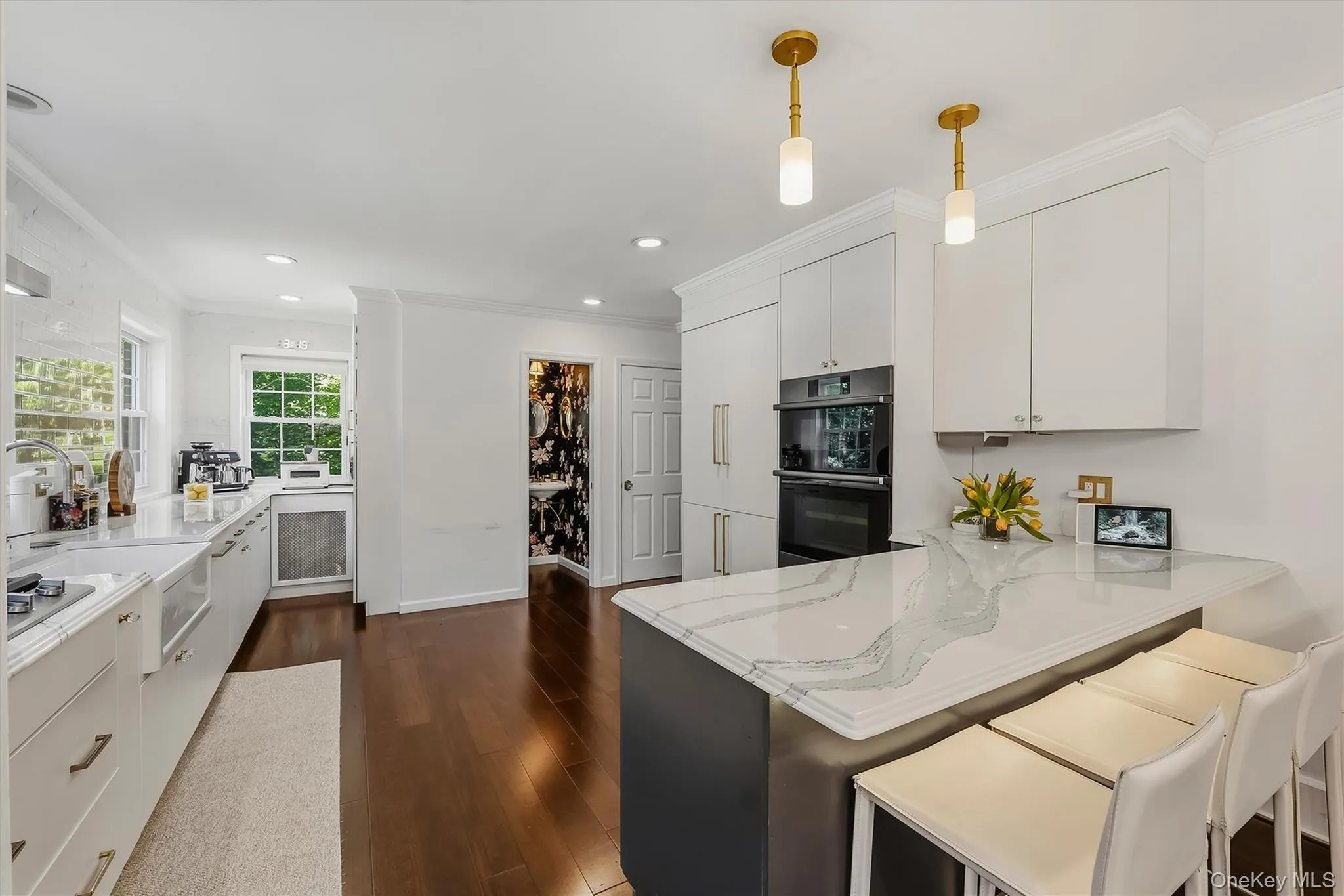 Kitchen featuring an island with a light-toned countertop, built-in double ovens, recessed lighting, and wood-finish flooring Kitchen featuring an island with a light-toned countertop, built-in double ovens, recessed lighting, and wood-finish flooring