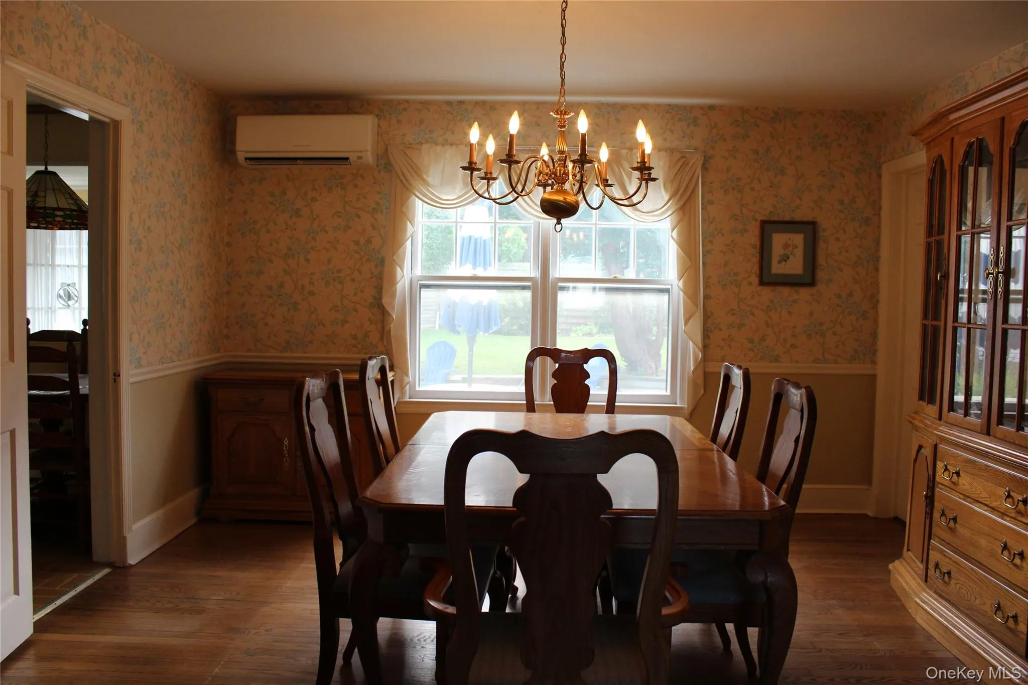 Hardwood flooring, window with exterior view, chandelier lighting, chair rail molding, wall-mounted AC unit Hardwood flooring, window with exterior view, chandelier lighting, chair rail molding, wall-mounted AC unit