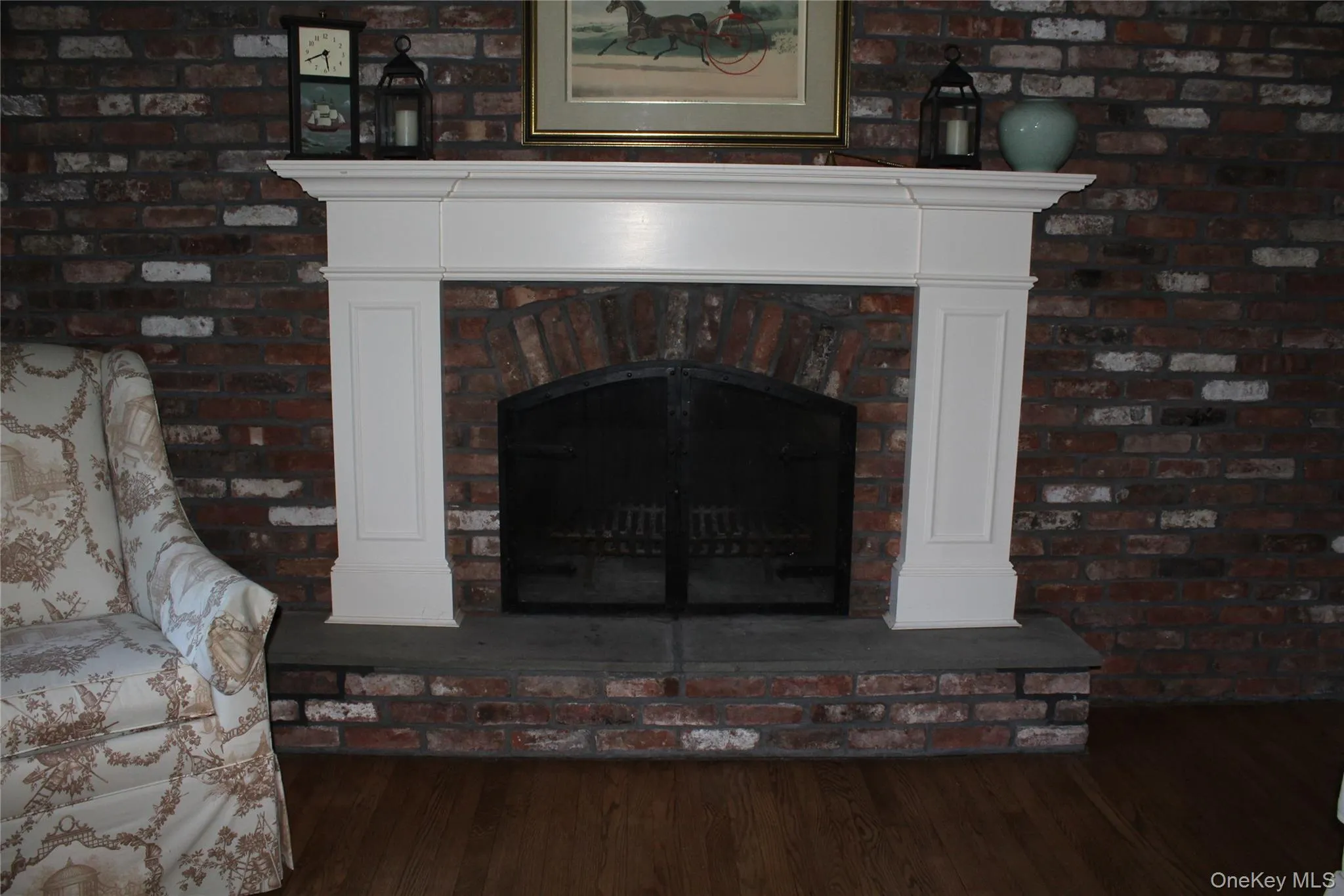 Brick-faced Wood Burning fireplace with a white mantel, arched firebox opening, and a dark stone hearth Brick-faced Wood Burning fireplace with a white mantel, arched firebox opening, and a dark stone hearth
