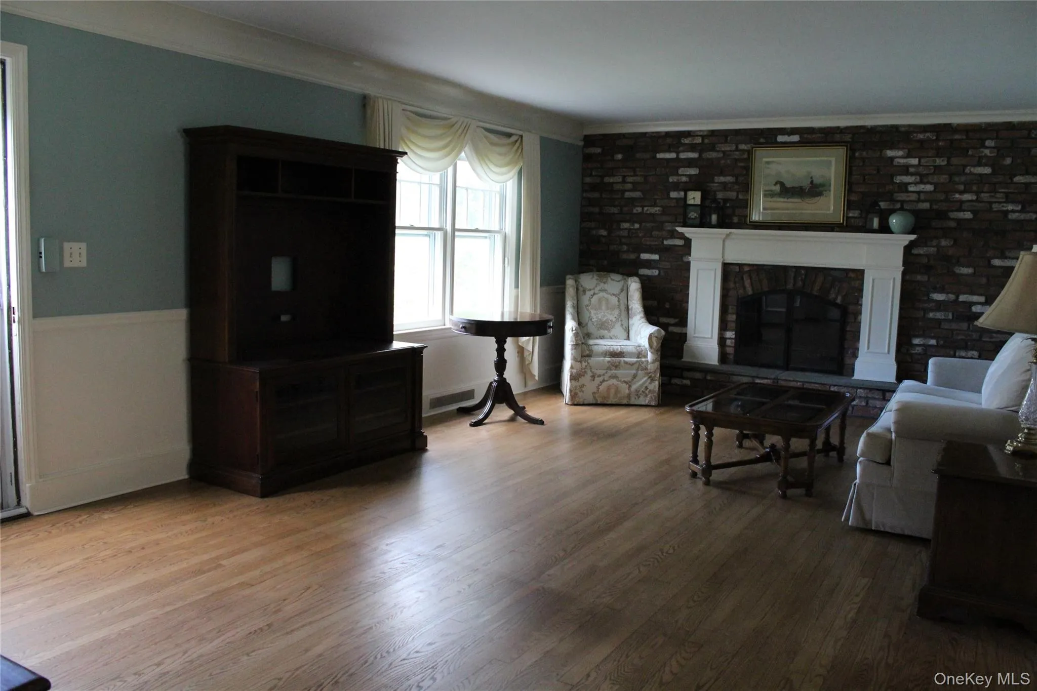 Hardwood flooring, brick-accented wall, classic white fireplace mantel Hardwood flooring, brick-accented wall, classic white fireplace mantel