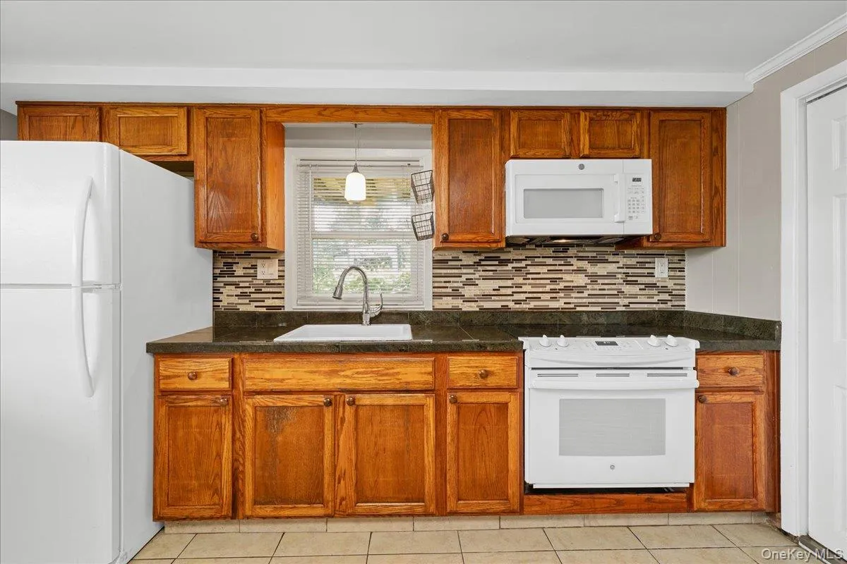 kitchen view with window over sink, microwave, electric oven and refrigerator. kitchen view with window over sink, microwave, electric oven and refrigerator.