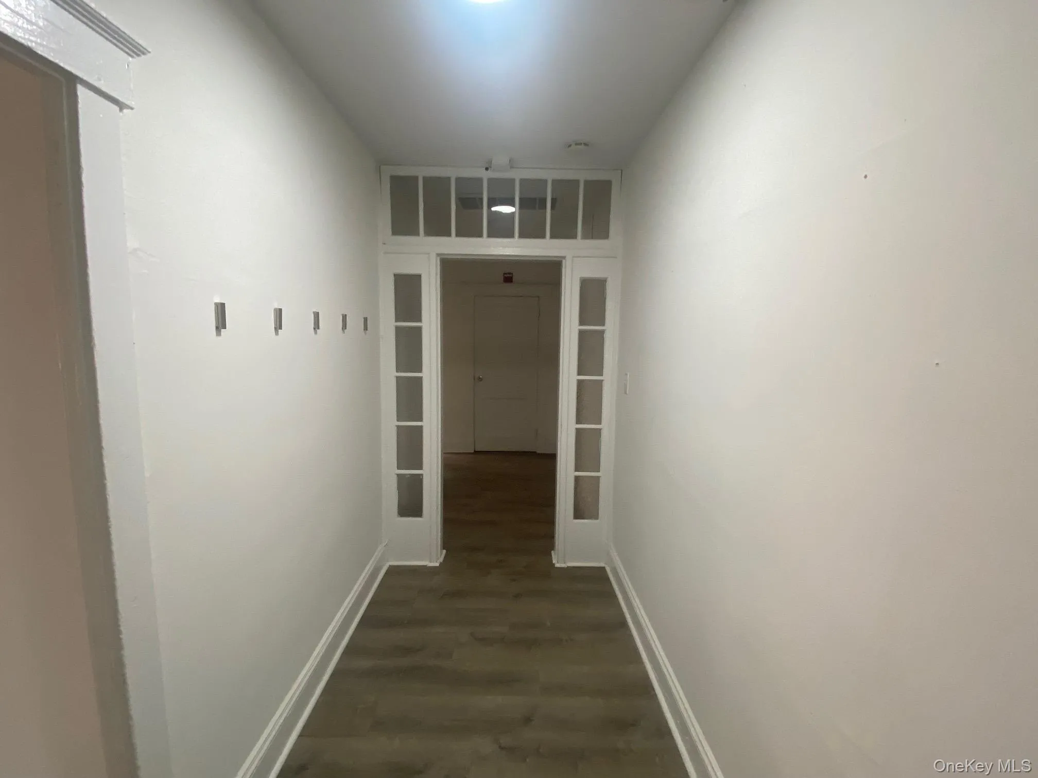 Hallway with dark wood-style flooring and baseboards Hallway with dark wood-style flooring and baseboards
