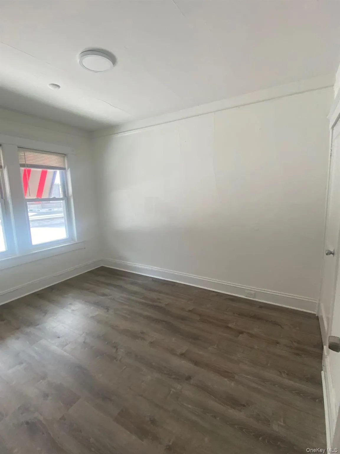 Empty room featuring dark wood-style floors and baseboards Empty room featuring dark wood-style floors and baseboards