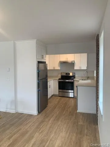 Kitchen featuring freestanding refrigerator, stainless steel range with electric cooktop, light countertops, and light wood finished floors Kitchen featuring freestanding refrigerator, stainless steel range with electric cooktop, light countertops, and light wood finished floors