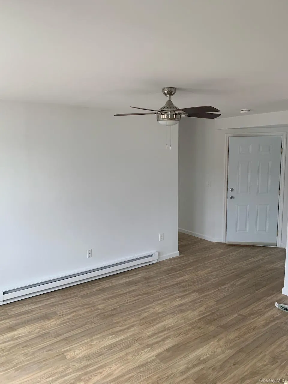 Unfurnished room featuring a baseboard heating unit, ceiling fan, and wood finished floors Unfurnished room featuring a baseboard heating unit, ceiling fan, and wood finished floors
