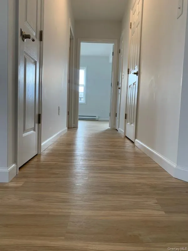 Corridor with light wood-style floors and a baseboard radiator Corridor with light wood-style floors and a baseboard radiator