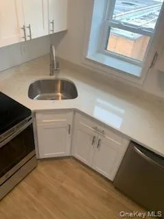 Kitchen featuring appliances with stainless steel finishes, white cabinetry, light countertops, and light wood-type flooring Kitchen featuring appliances with stainless steel finishes, white cabinetry, light countertops, and light wood-type flooring