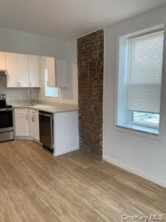 Kitchen featuring stainless steel appliances, light countertops, light wood-style flooring, and white cabinetry Kitchen featuring stainless steel appliances, light countertops, light wood-style flooring, and white cabinetry