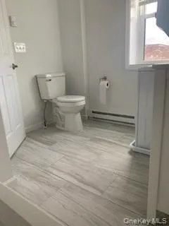 Bathroom featuring a baseboard heating unit and toilet Bathroom featuring a baseboard heating unit and toilet