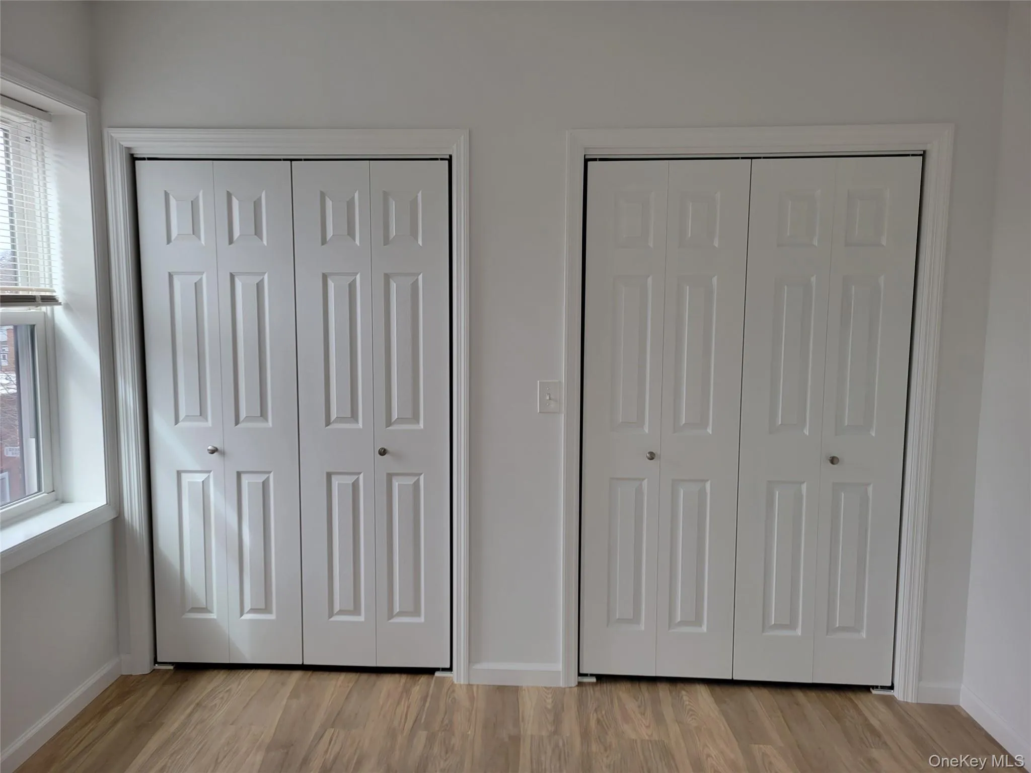 Unfurnished bedroom with light wood-style floors and multiple closets Unfurnished bedroom with light wood-style floors and multiple closets
