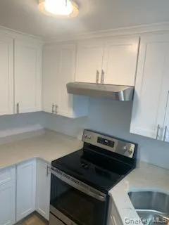 Kitchen featuring stainless steel range with electric cooktop, ventilation hood, and white cabinetry Kitchen featuring stainless steel range with electric cooktop, ventilation hood, and white cabinetry