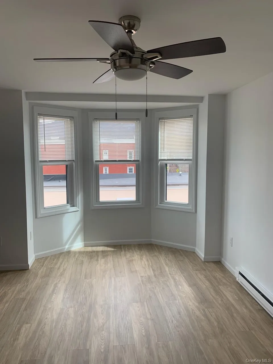 Spare room featuring wood finished floors, a baseboard heating unit, and a ceiling fan Spare room featuring wood finished floors, a baseboard heating unit, and a ceiling fan